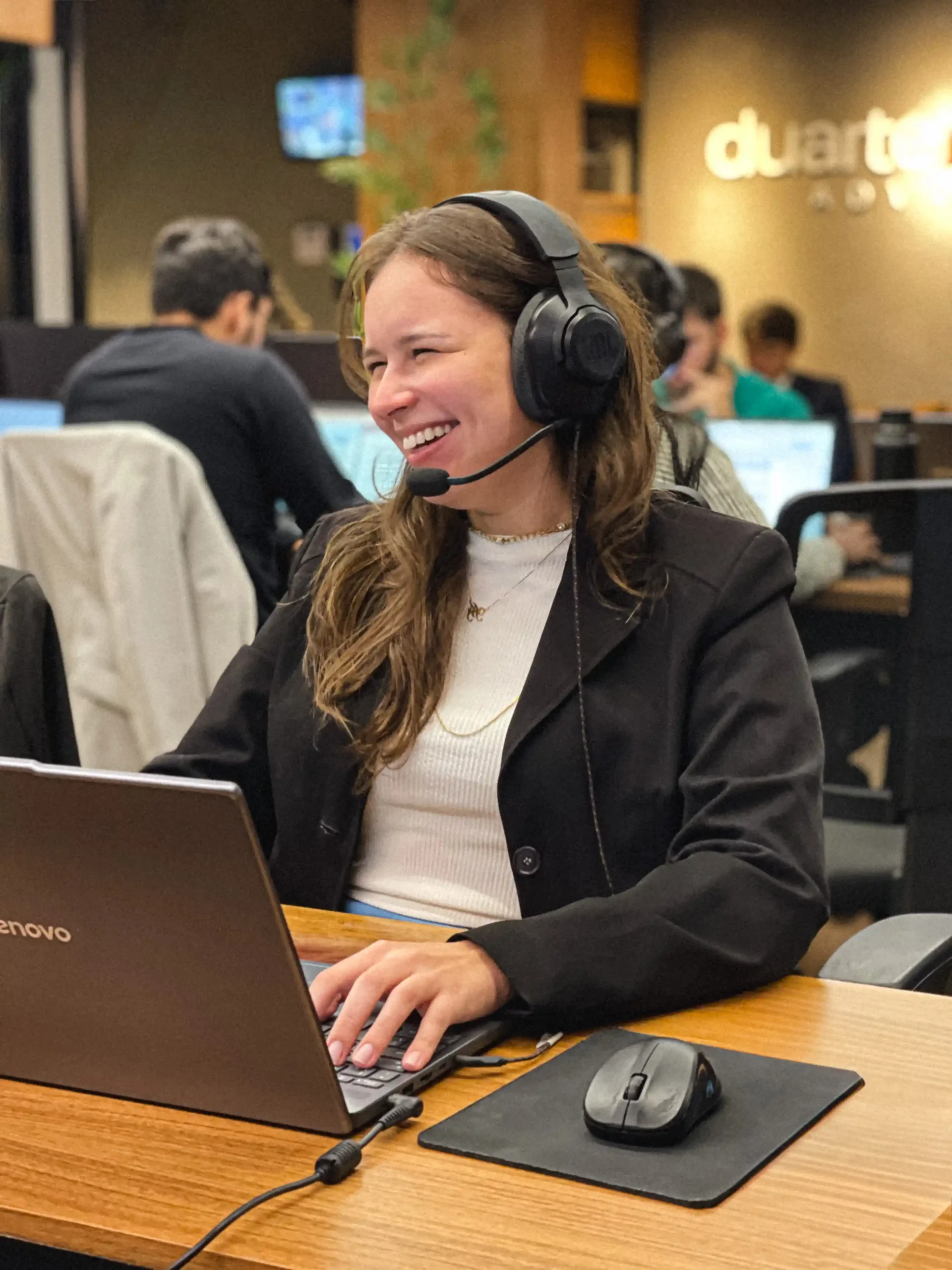 Integrante do escritório com headset sorrindo durante atendimento remoto no notebook
