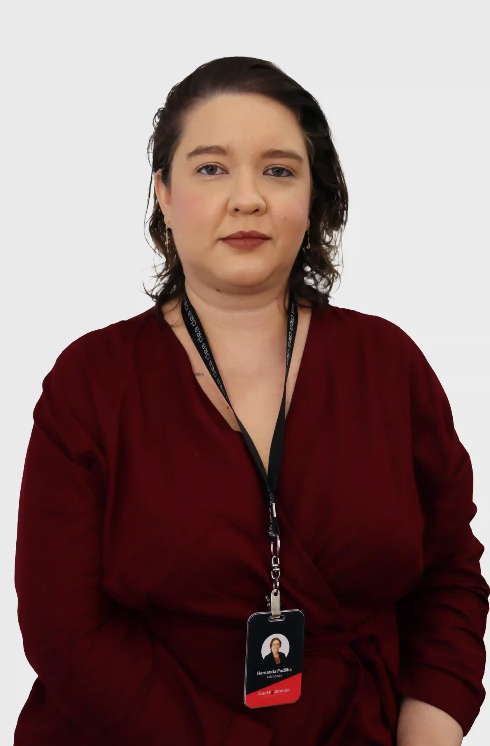 Advogada do escritório de blusa bordô transpassada e crachá, em retrato frontal