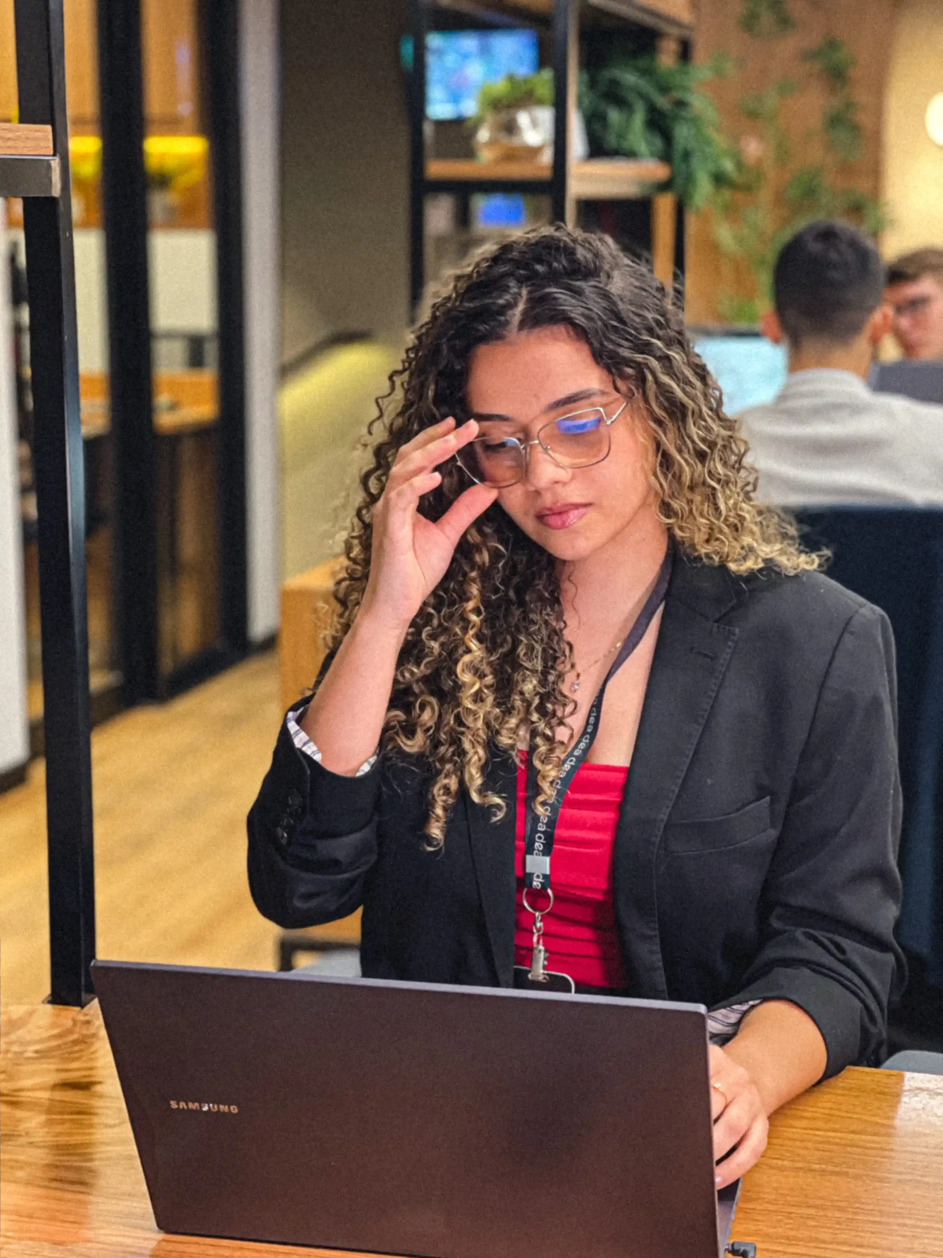 Integrante do escritório de blazer preto e óculos concentrada na leitura no notebook