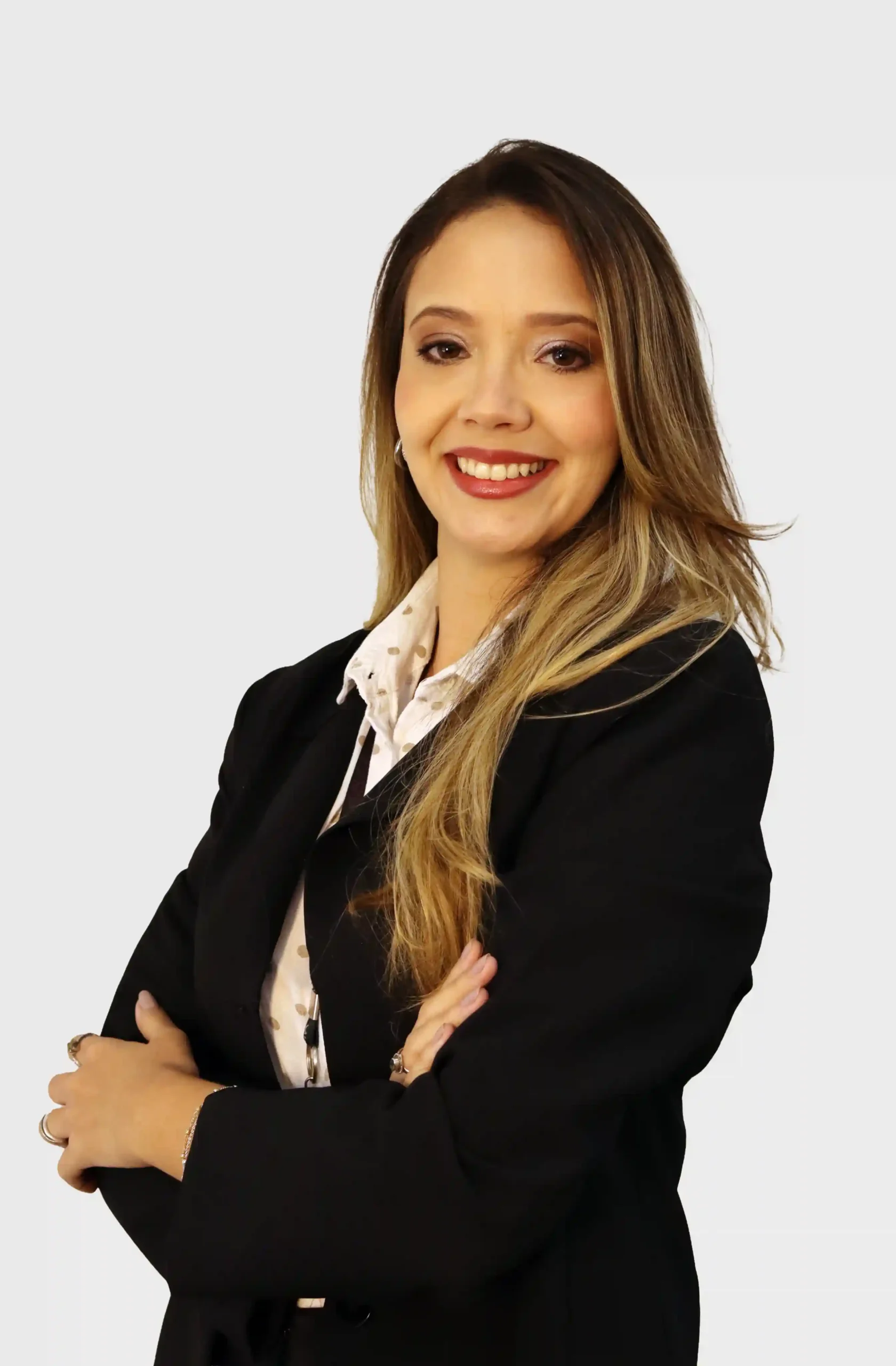 Integrante do escritório de blazer preto e camisa de poá, de braços cruzados e sorrindo