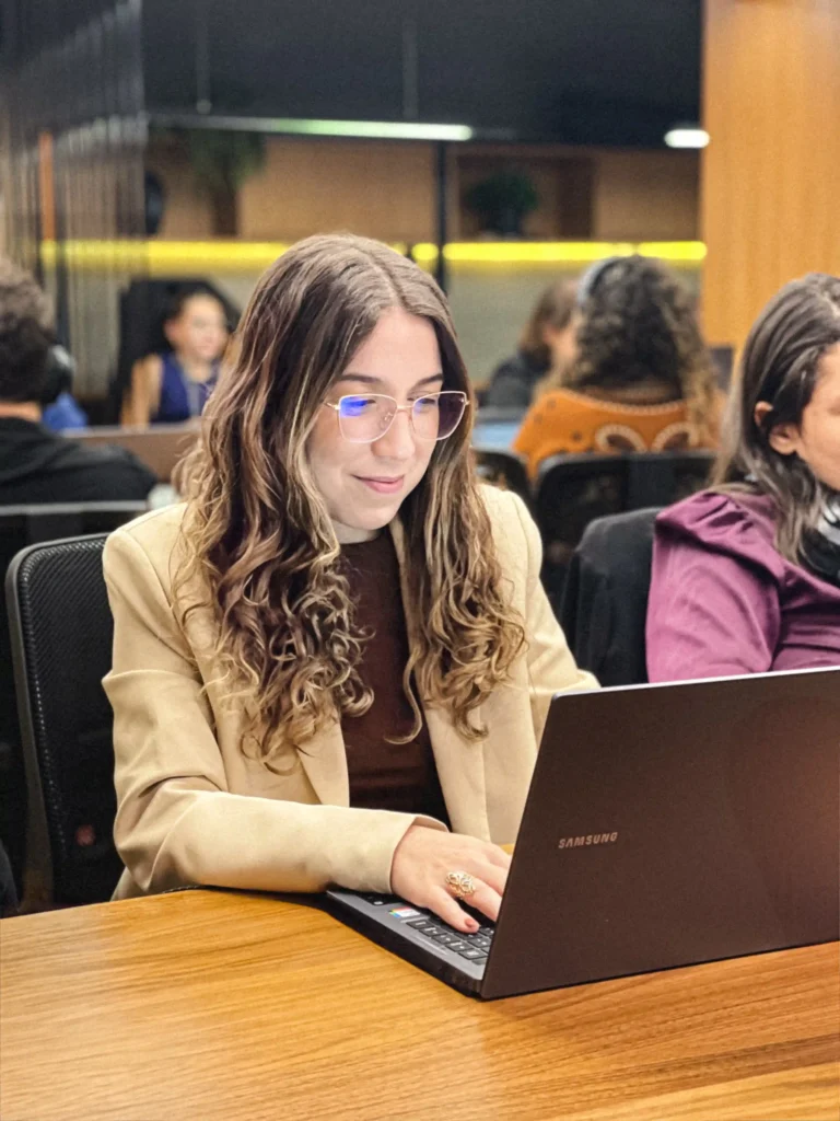 Integrante do escritório de blazer bege e óculos digitando no notebook