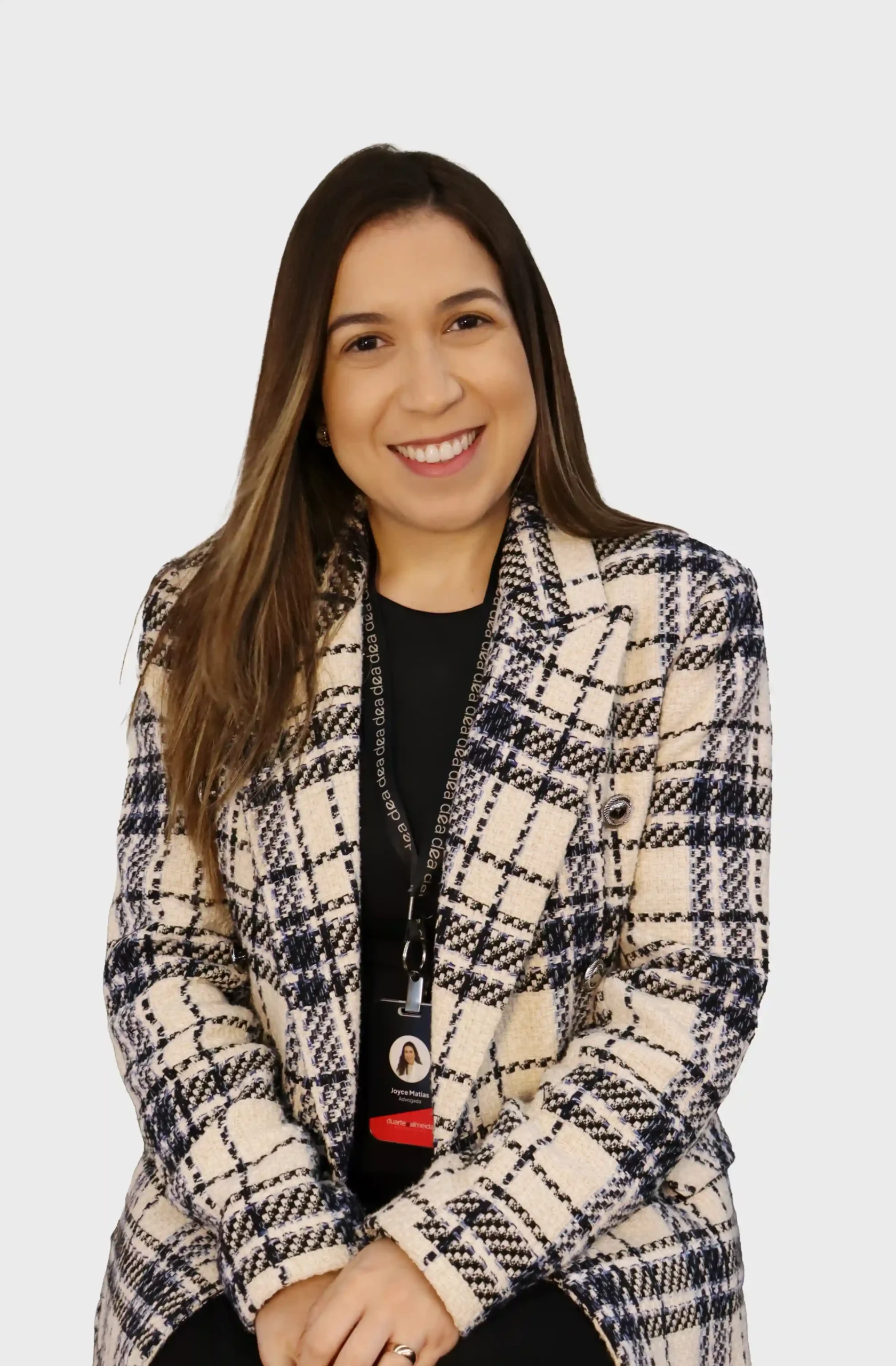 Advogada do escritório de blazer xadrez em tweed e crachá, sentada e sorrindo