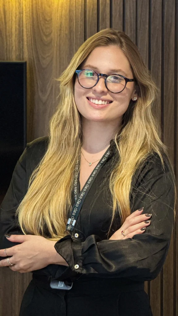 Integrante do escritório de camisa preta e óculos sorrindo de braços cruzados