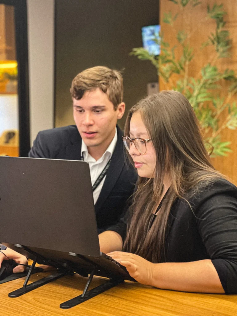 Dois integrantes do escritório acompanhando juntos a tela do notebook