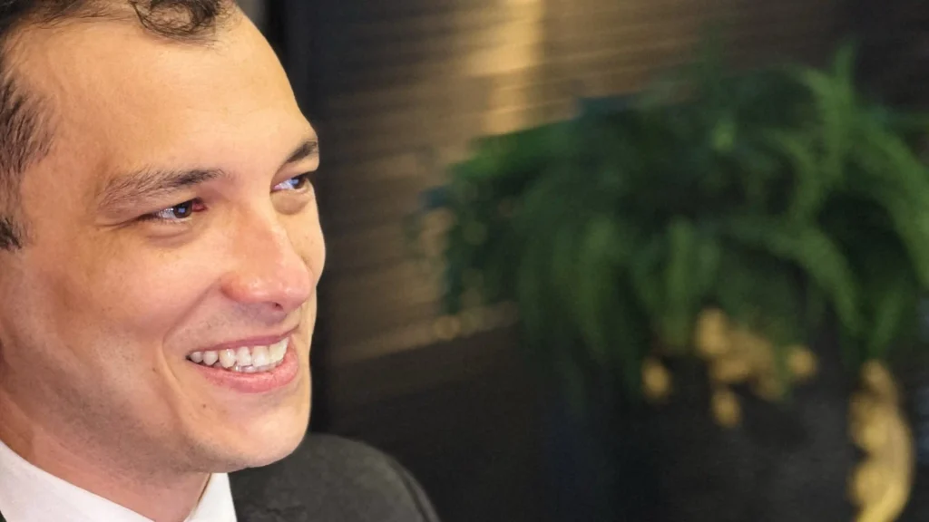 Close de sócio do escritório sorrindo, com planta desfocada ao fundo