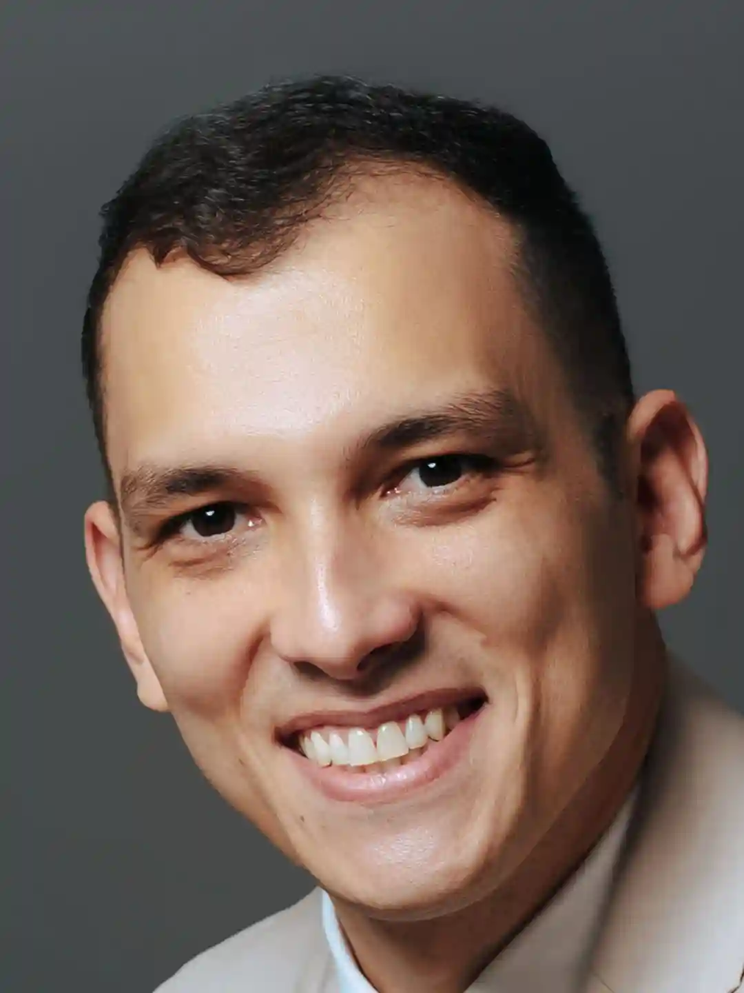 Retrato em close de integrante do escritório de terno claro sorrindo em fundo cinza