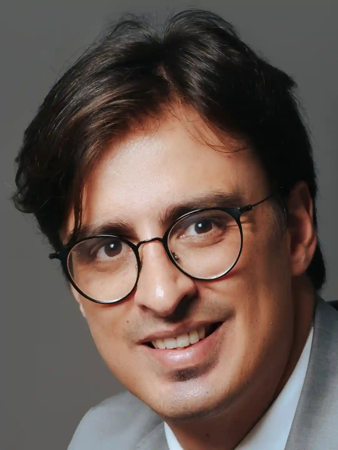 Retrato em close de integrante do escritório de óculos e terno claro sorrindo