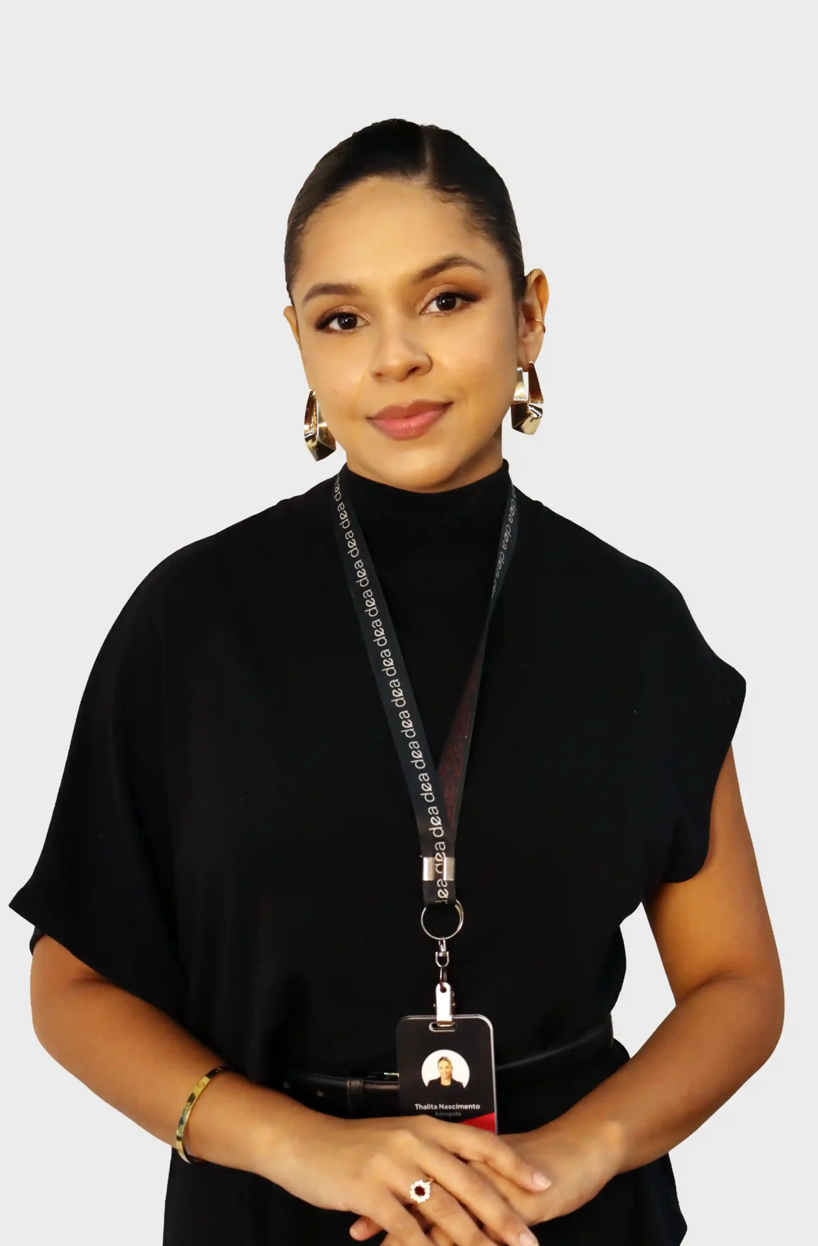 Advogada do escritório de blusa preta de gola alta, brincos dourados e crachá, com as mãos unidas