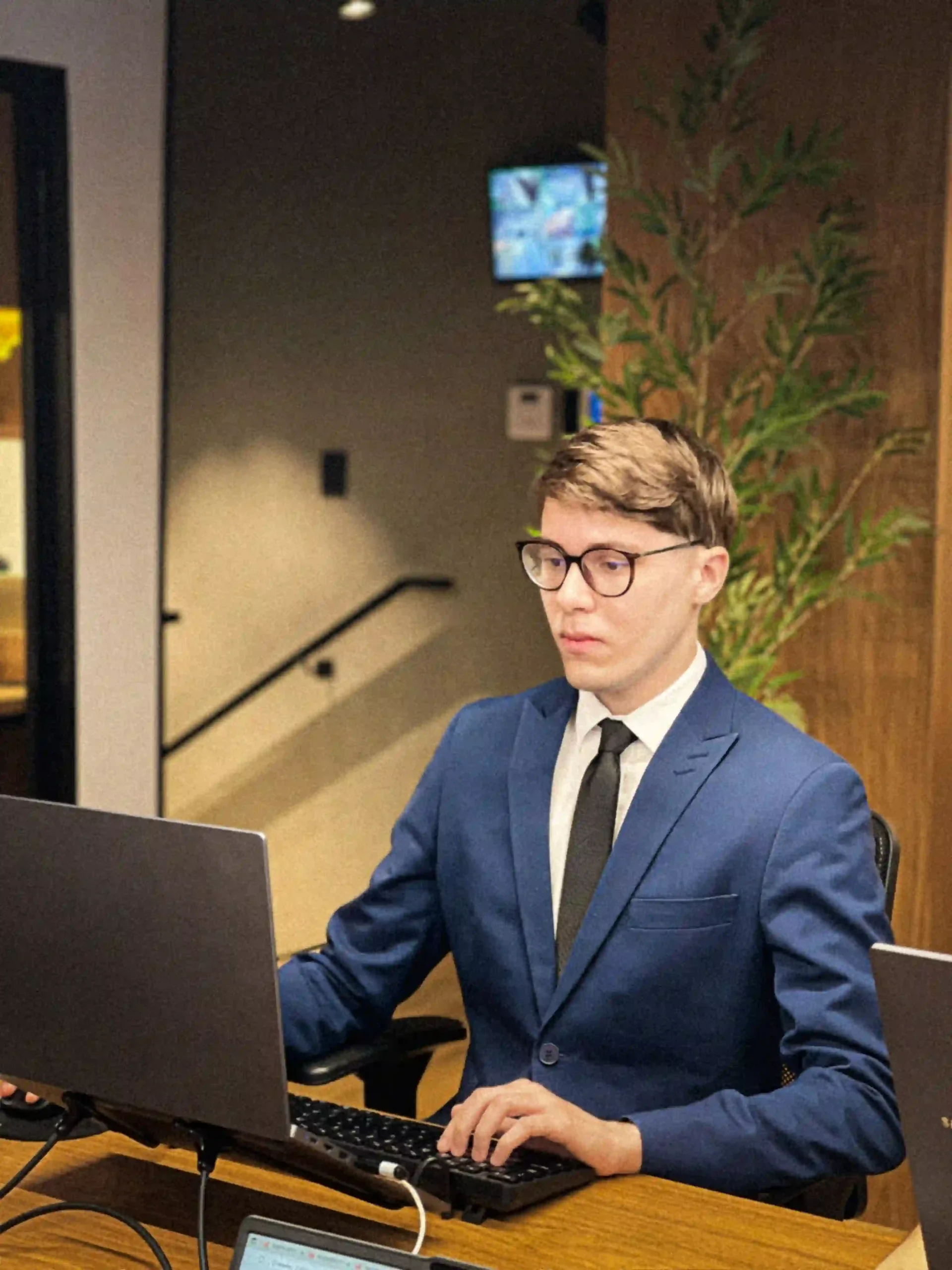 Advogado de terno azul e óculos em atendimento ao computador na recepção do escritório