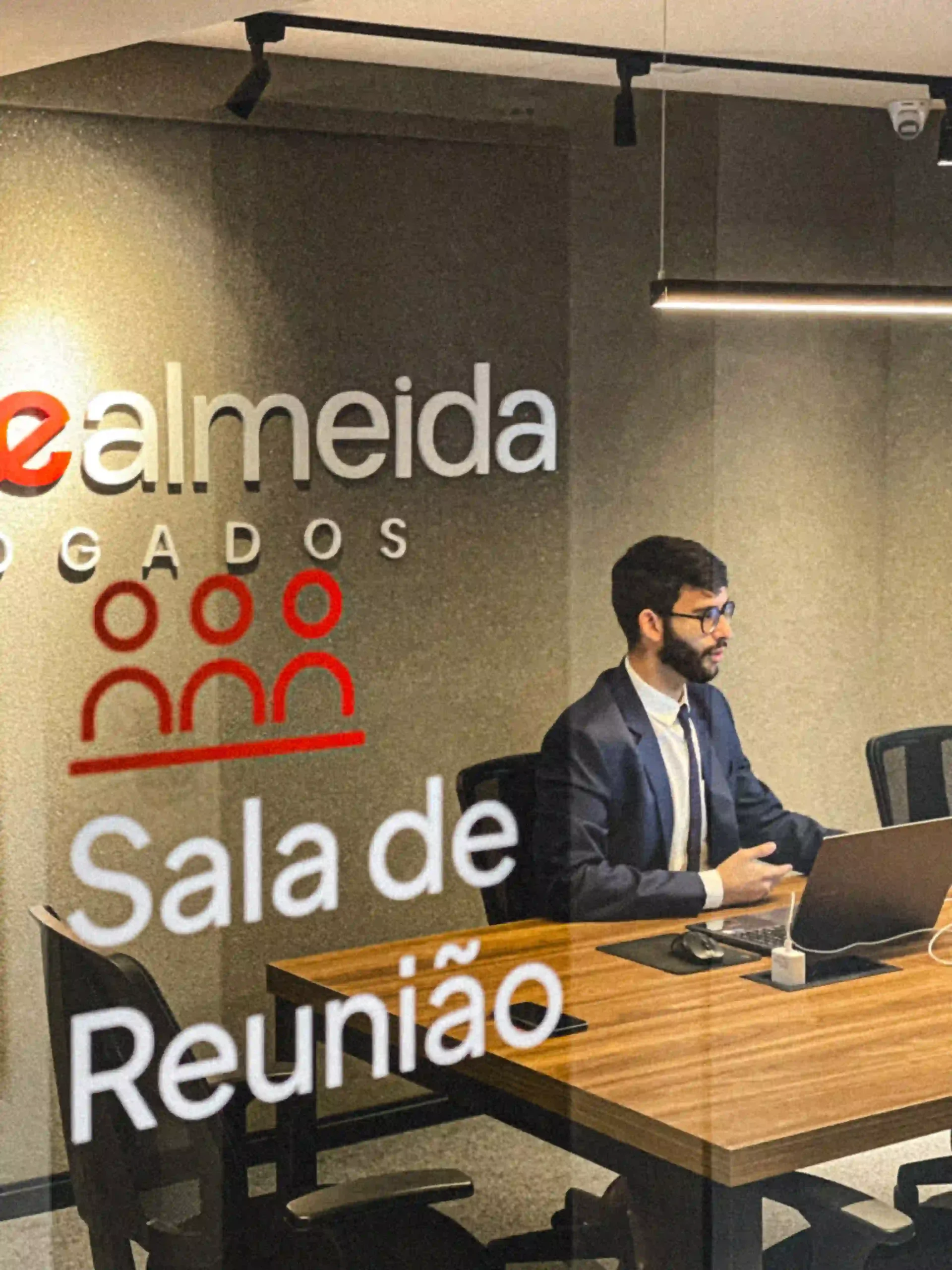 Advogado de terno em atendimento na sala de reunião sinalizada do escritório