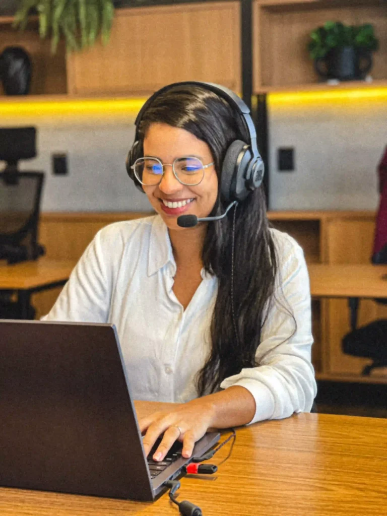 Integrante do Duarte e Almeida Advogados de headset sorrindo durante atendimento ao notebook