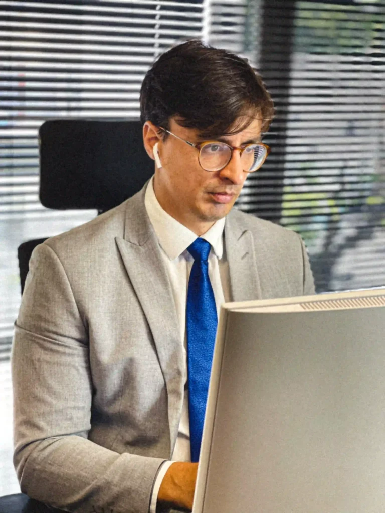 Ricardo Duarte Jr., sócio do escritório, de terno claro em atendimento ao computador